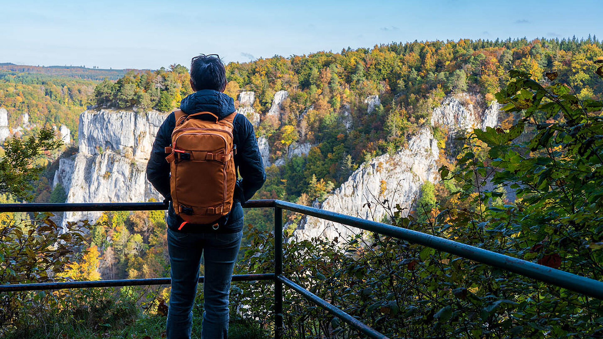Wanderer mit Rucksack genießt den Ausblick auf die Felsenlandschaft im Donautal.