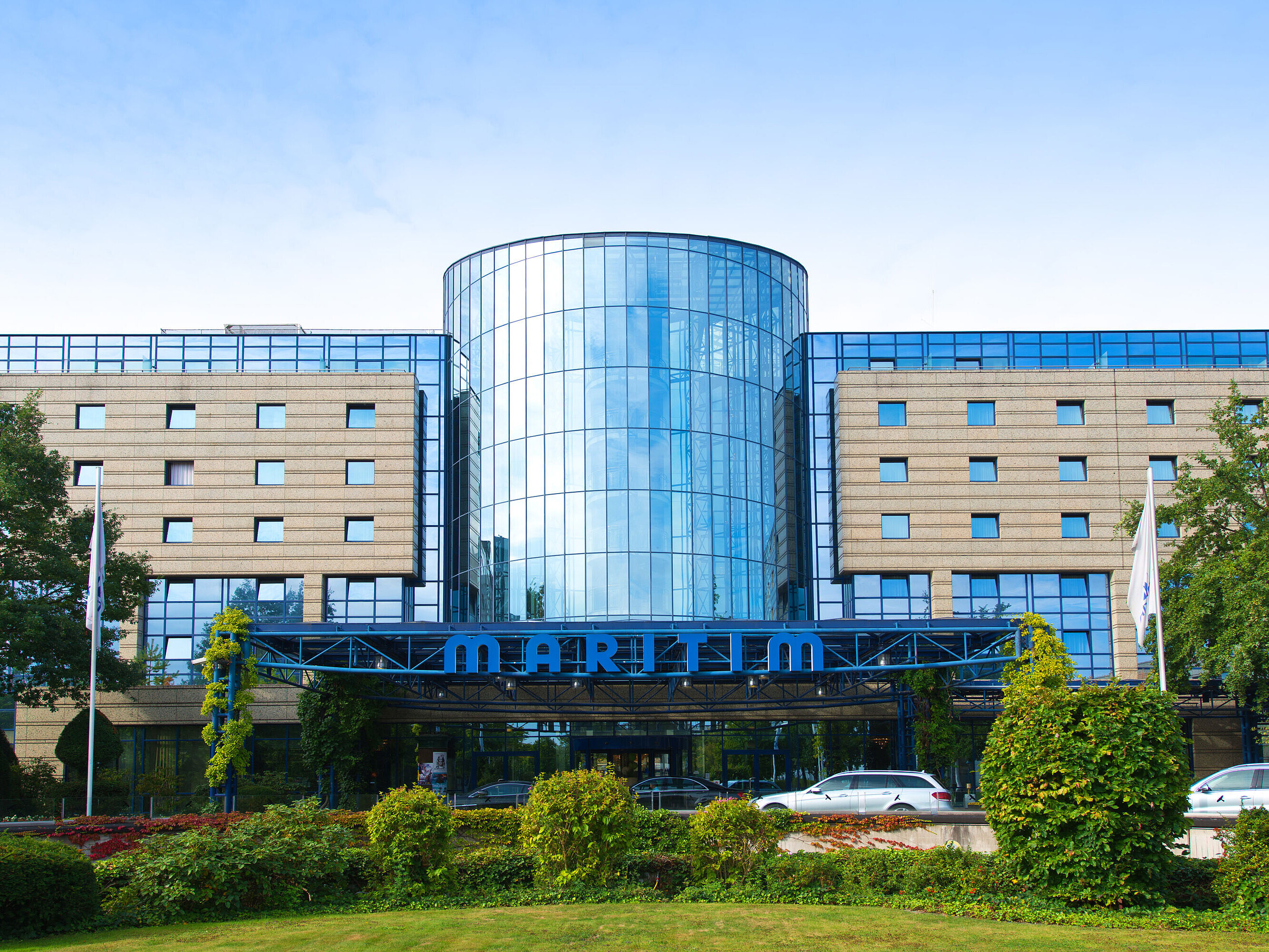Außenansicht des Maritim Hotels Bonn mit moderner Glasfassade und gepflegter Gartenanlage im Vordergrund.