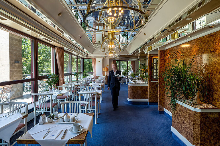 Restaurant im Maritim Hotel Köln mit Servicekraft und großen Fenstern mit Blick ins Grüne