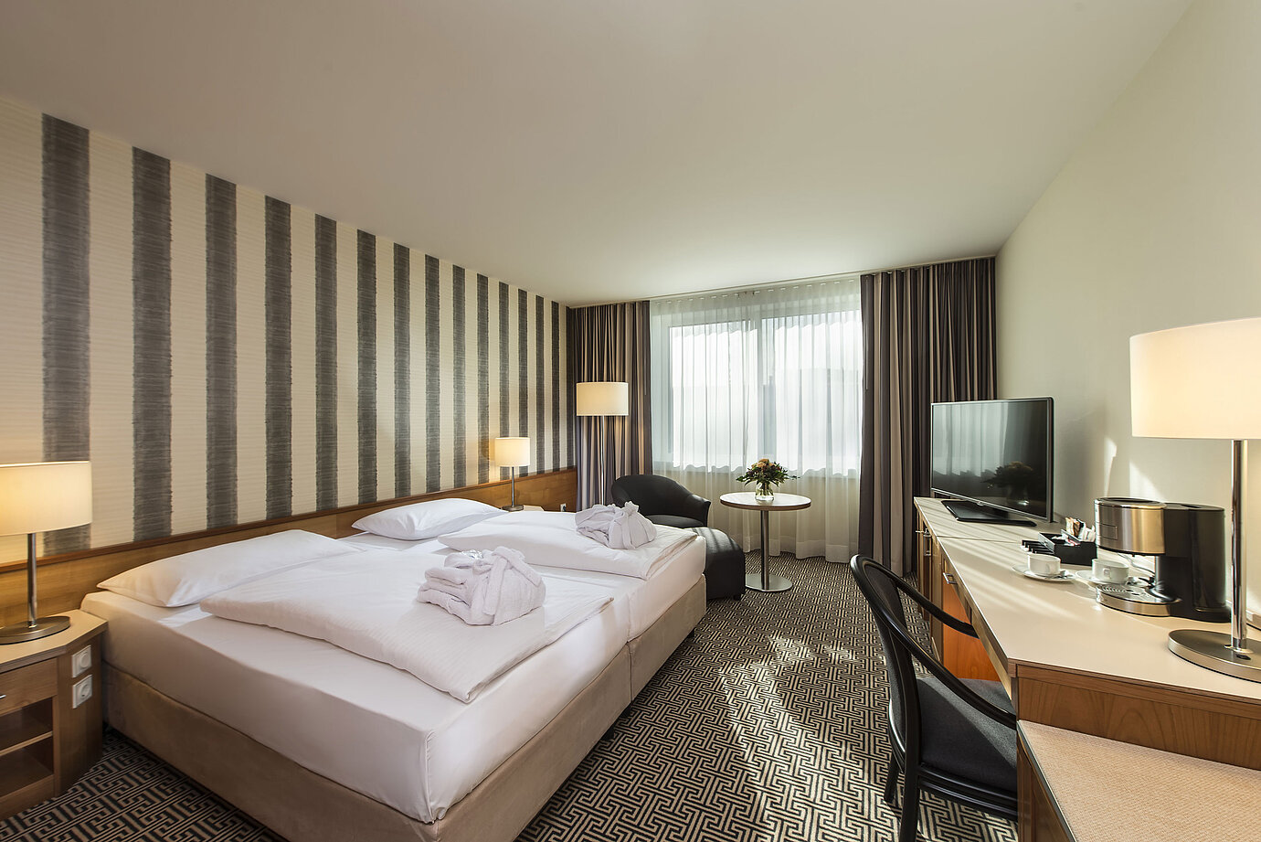 Helles Doppelzimmer mit Schreibtisch, Sesseln und großem Bett im Maritim Hotel Stuttgart