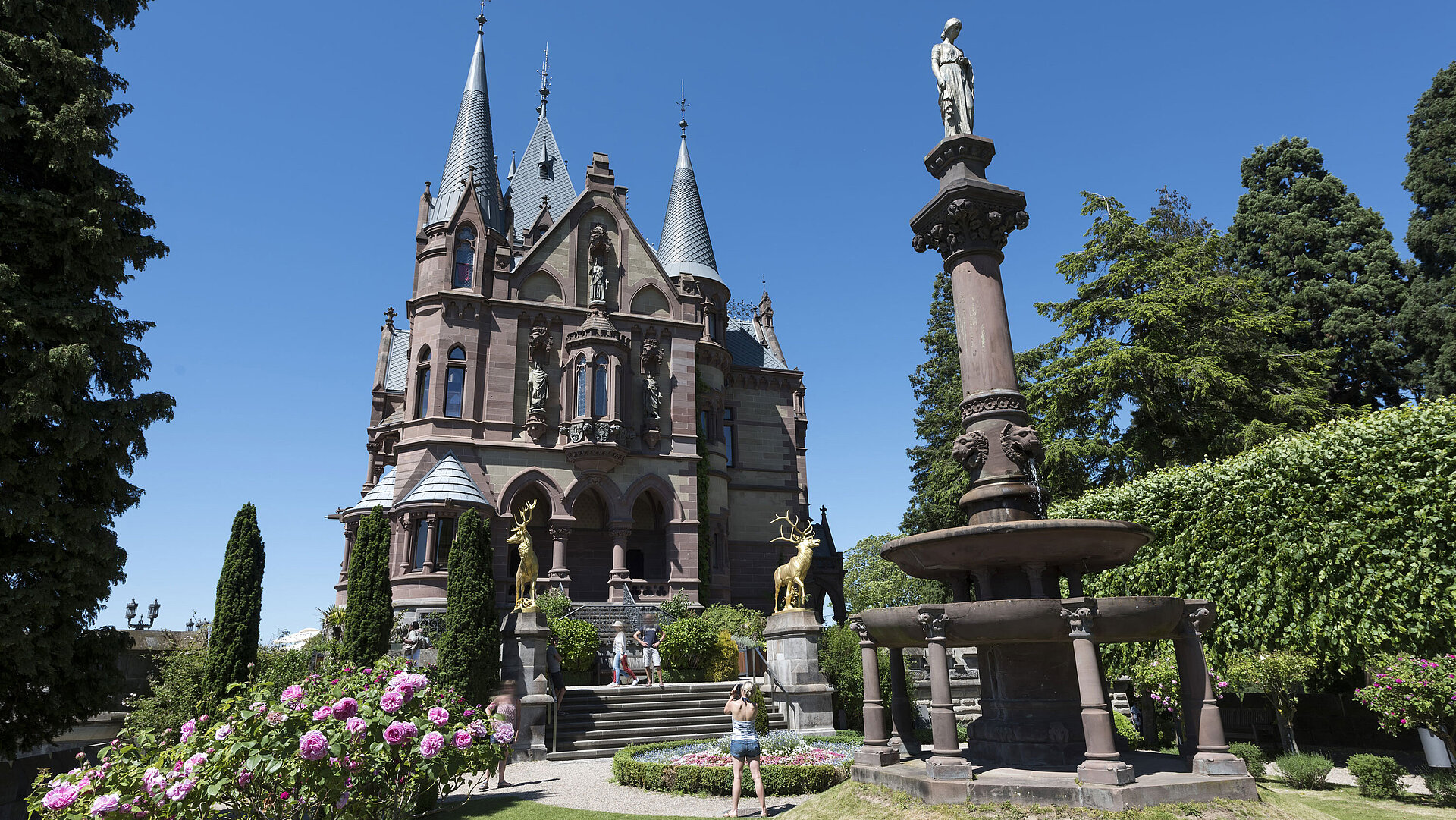 Das prachtvolle Schloss Drachenburg mit einem kunstvollen Brunnen und blühendem Garten.