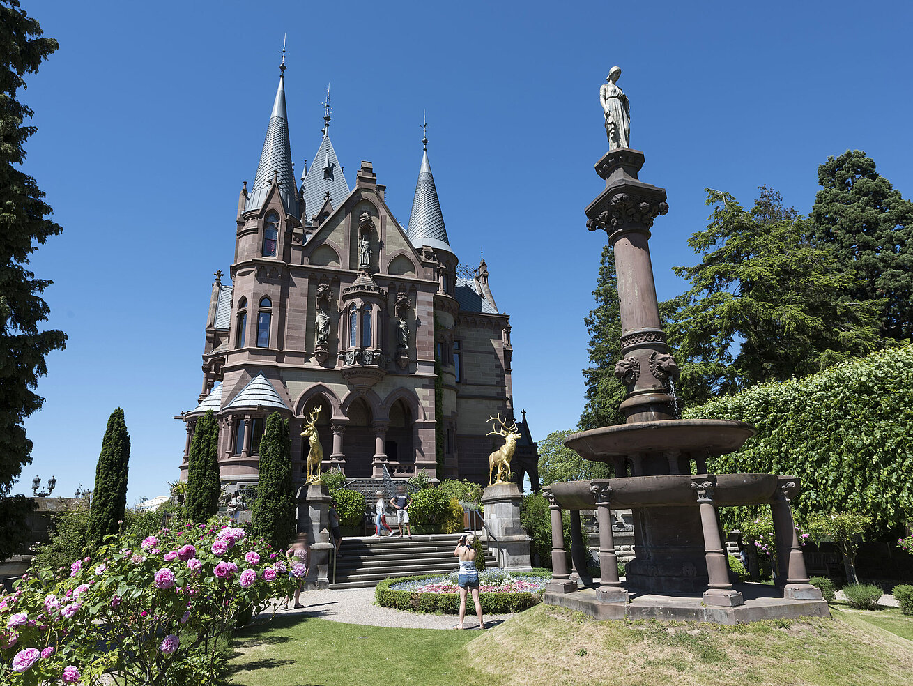 Das prachtvolle Schloss Drachenburg mit einem kunstvollen Brunnen und blühendem Garten.