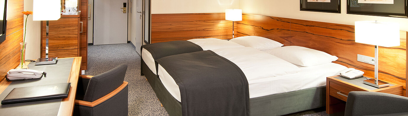 Doppelzimmer mit Holzdetails, Sitzgruppe und Schreibtisch im Maritim Hotel München
