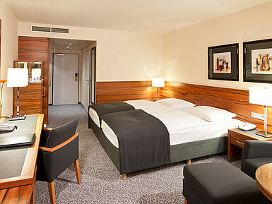 Doppelzimmer mit Holzdetails, Sitzgruppe und Schreibtisch im Maritim Hotel München