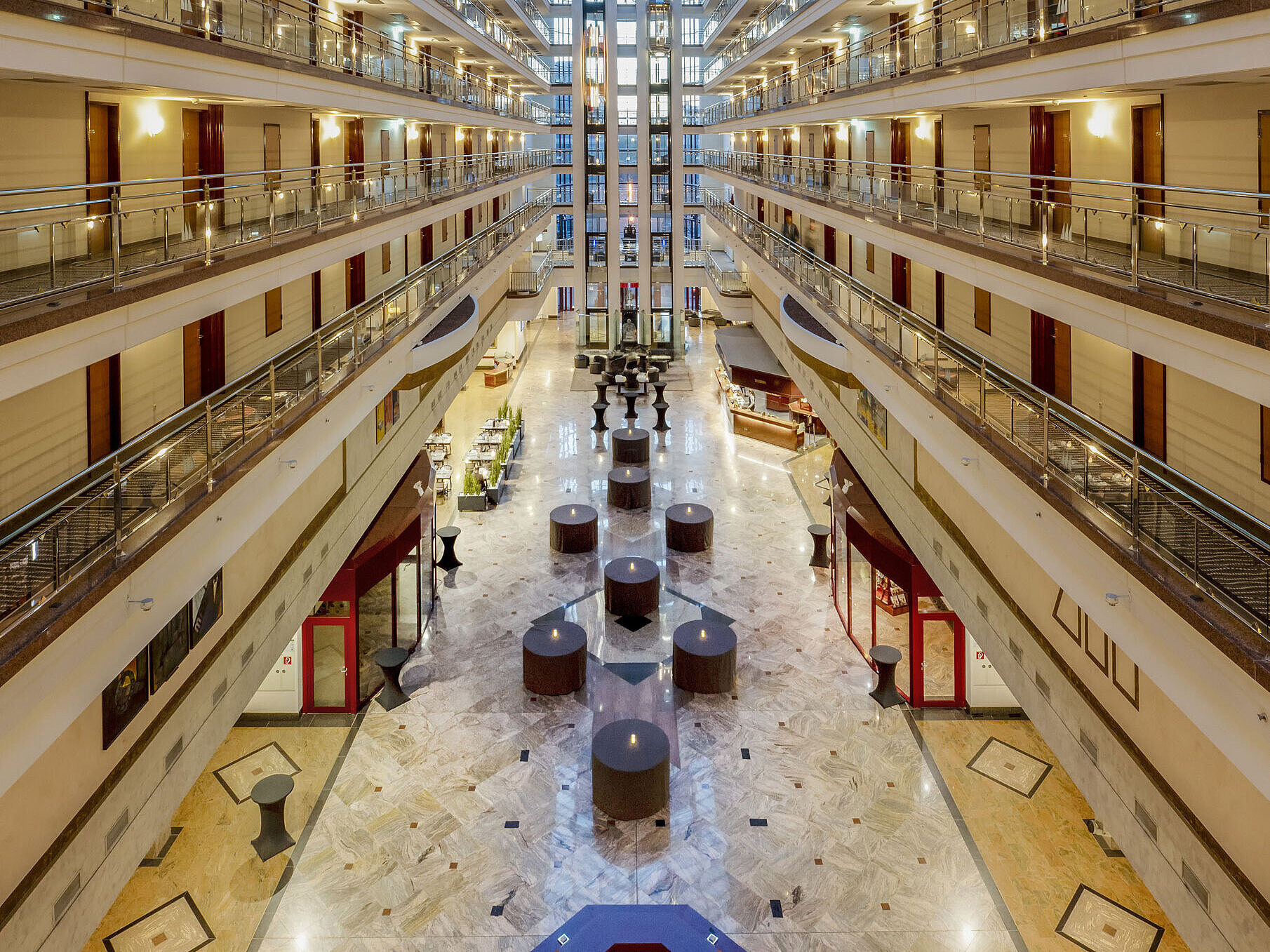 Beeindruckende Hotellobby mit Glasdach, mehreren Etagen und Sitzbereichen, die ein großzügiges und elegantes Ambiente schaffen.