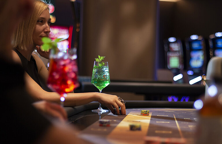 Frau mit Cocktail und Spielchips am Tisch im Casino des Maritim Hotel Plaza Tirana