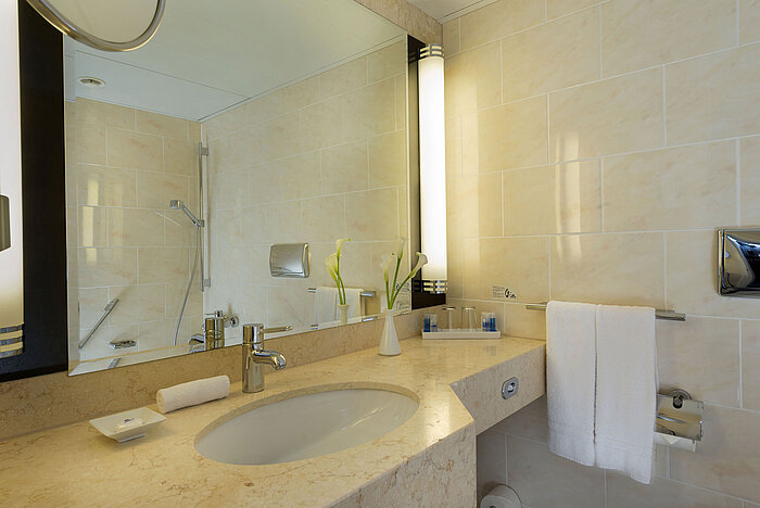 Modernes Badezimmer im Maritim Hotel Fulda mit Marmorwaschtisch, großer Spiegel und begehbarer Dusche.