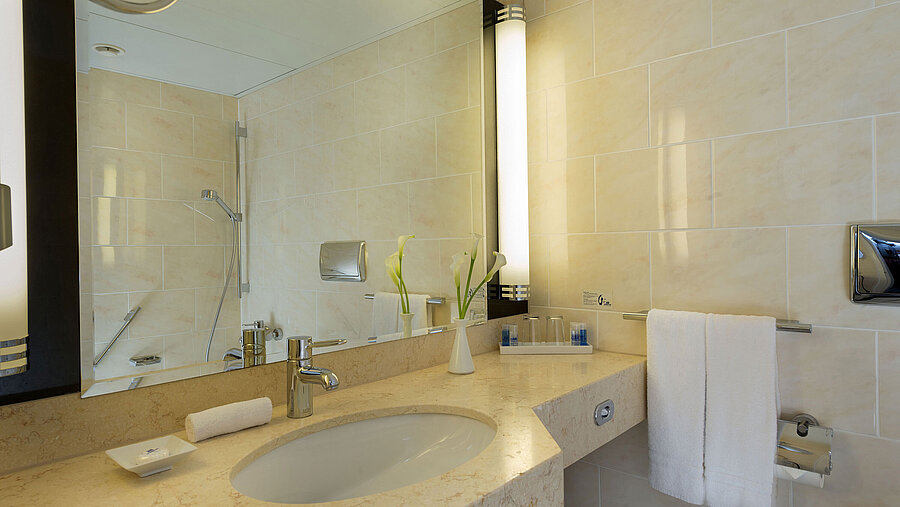 Modernes Badezimmer im Maritim Hotel Fulda mit Marmorwaschtisch, großer Spiegel und begehbarer Dusche.