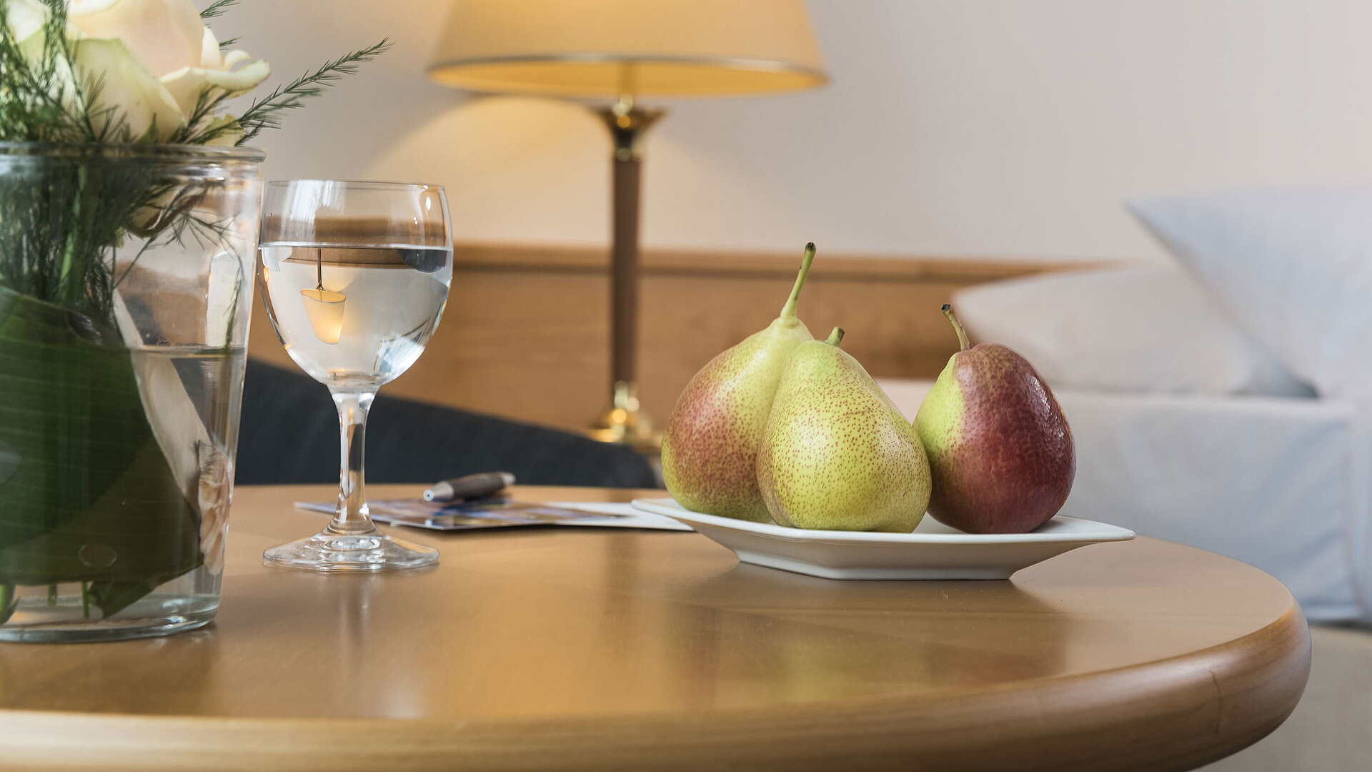 Gemütliches Hotelzimmer mit einer Platte Früchte und einem Glas Wasser auf dem Tisch