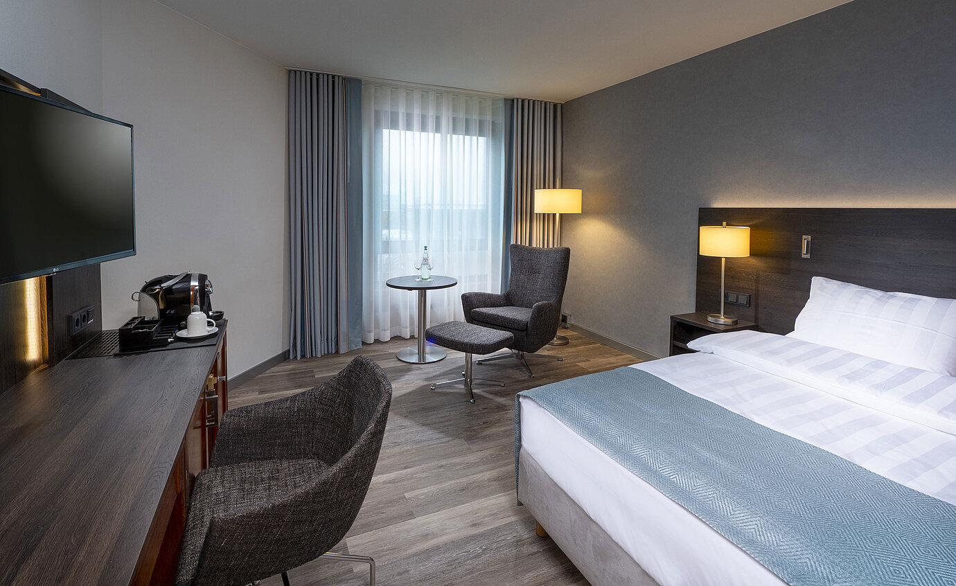 Modern eingerichtetes Superior Queen Zimmer mit Schreibtisch, Fernseher, Sitzbereich und komfortablem Bett im Maritim Bremen.