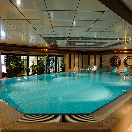 Innenpool im Maritim Hotel Köln mit Liegestühlen und Pflanzen für eine entspannende Atmosphäre.