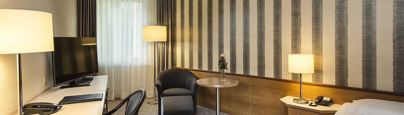 Schreibtisch mit TV und komfortabler Sitzmöglichkeit im Einzelzimmer des Maritim Hotel Stuttgart