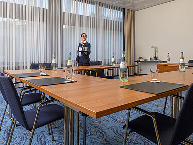 Tagungsraum mit U-Bestuhlung und freundlicher Maritim-Mitarbeiterin im Maritim Hotel Travemünde