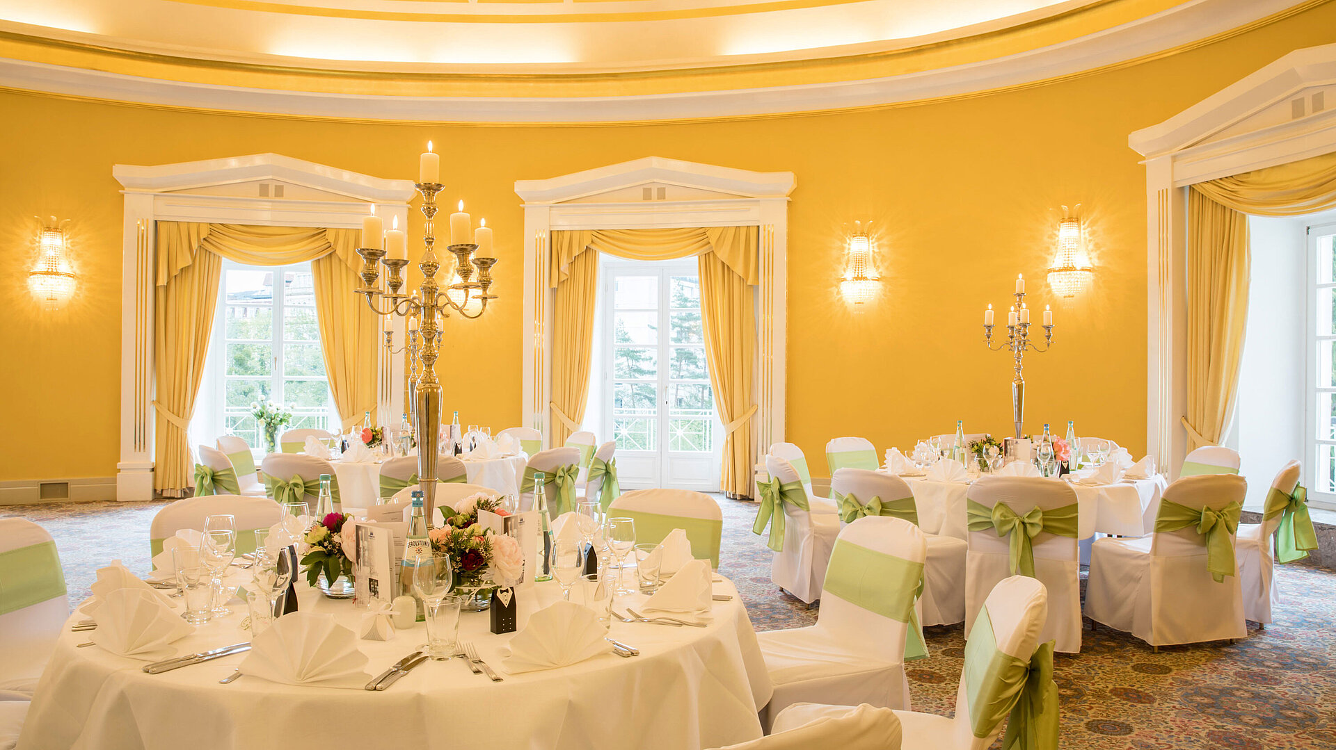 Festlich gedeckter Saal mit weißen Hussen und grünen Schleifen für Hochzeiten im Maritim Hotel Bad Wildungen