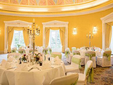 Festlich gedeckter Saal mit weißen Hussen und grünen Schleifen für Hochzeiten im Maritim Hotel Bad Wildungen