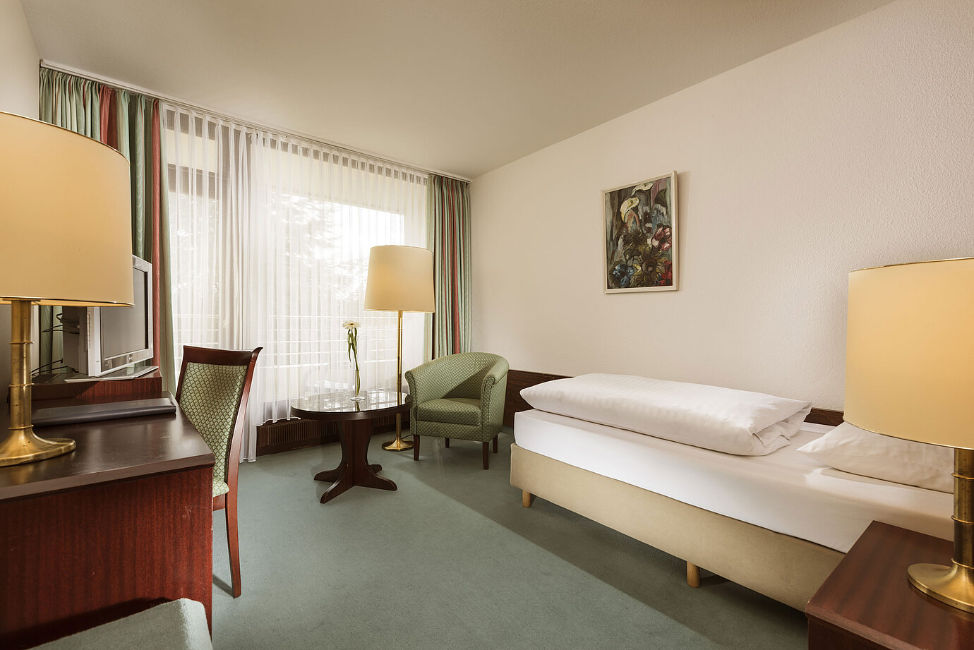 Freundliches Einzelzimmer mit Sessel, Schreibtisch und großem Fenster im Maritim Hotel Bad Salzuflen