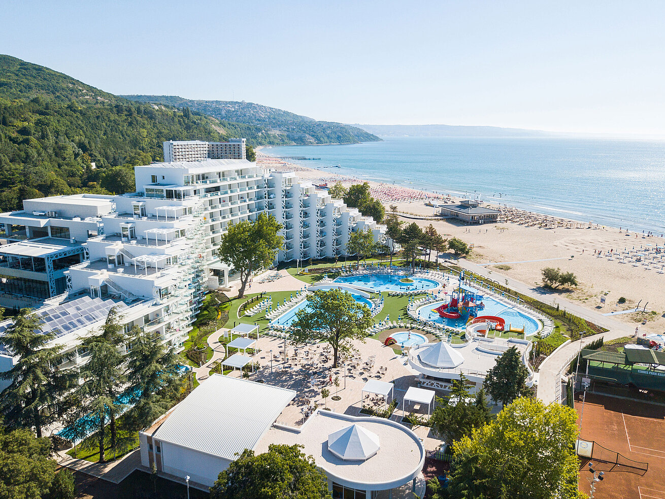 Luftaufnahme des Resorts mit Pools, Strand, modernem Hotelgebäude und Blick auf das Meer und die Küste
