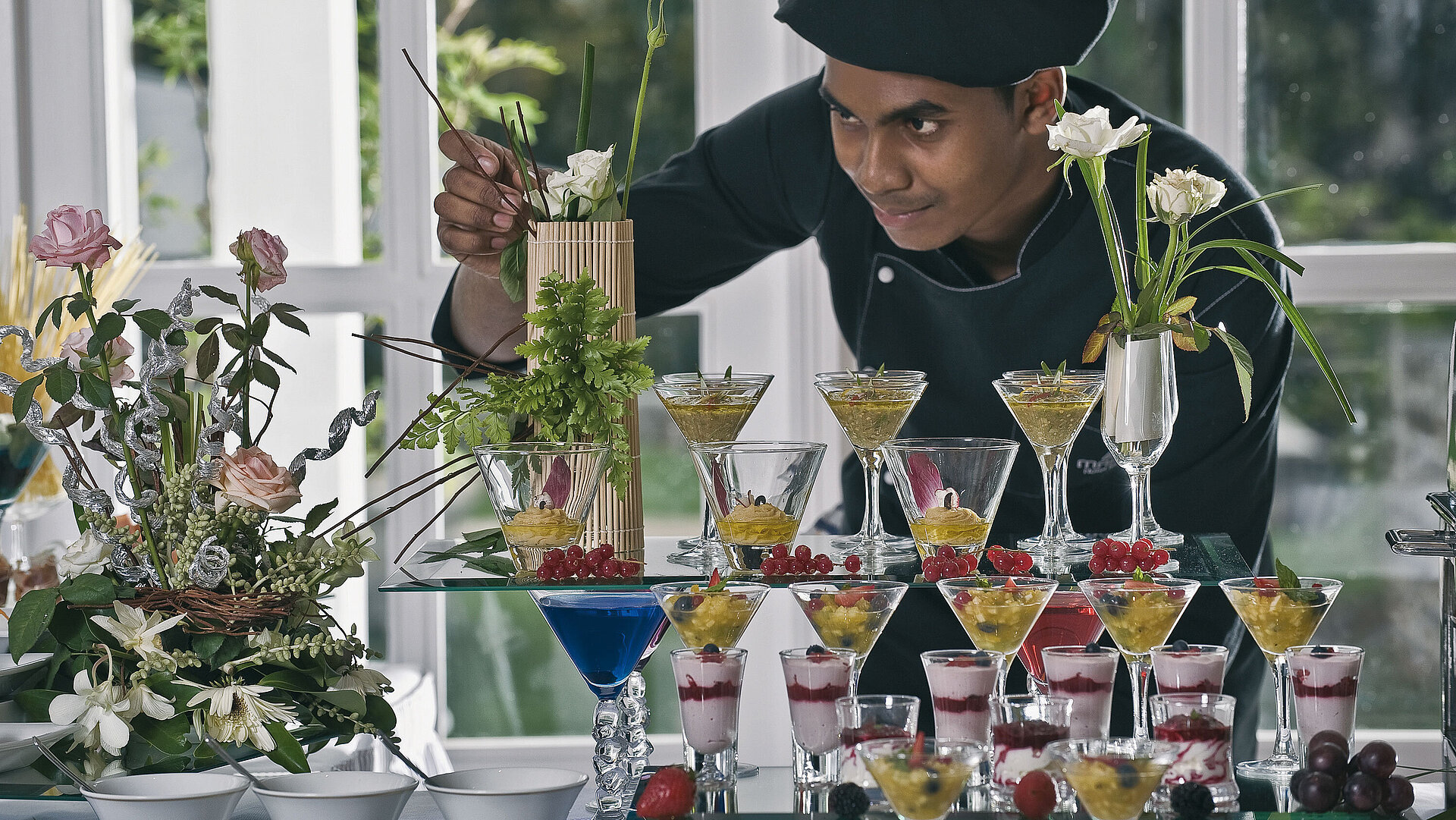 Koch dekoriert kunstvolle Desserts und Gläser bei elegantem Dessertbuffet