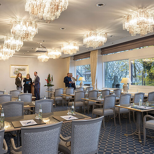Der Salon Kopenhagen im Maritim Hotel Kiel, ein eleganter Konferenzraum mit Kronleuchtern, gedeckten Tischen und großen Fenstern.