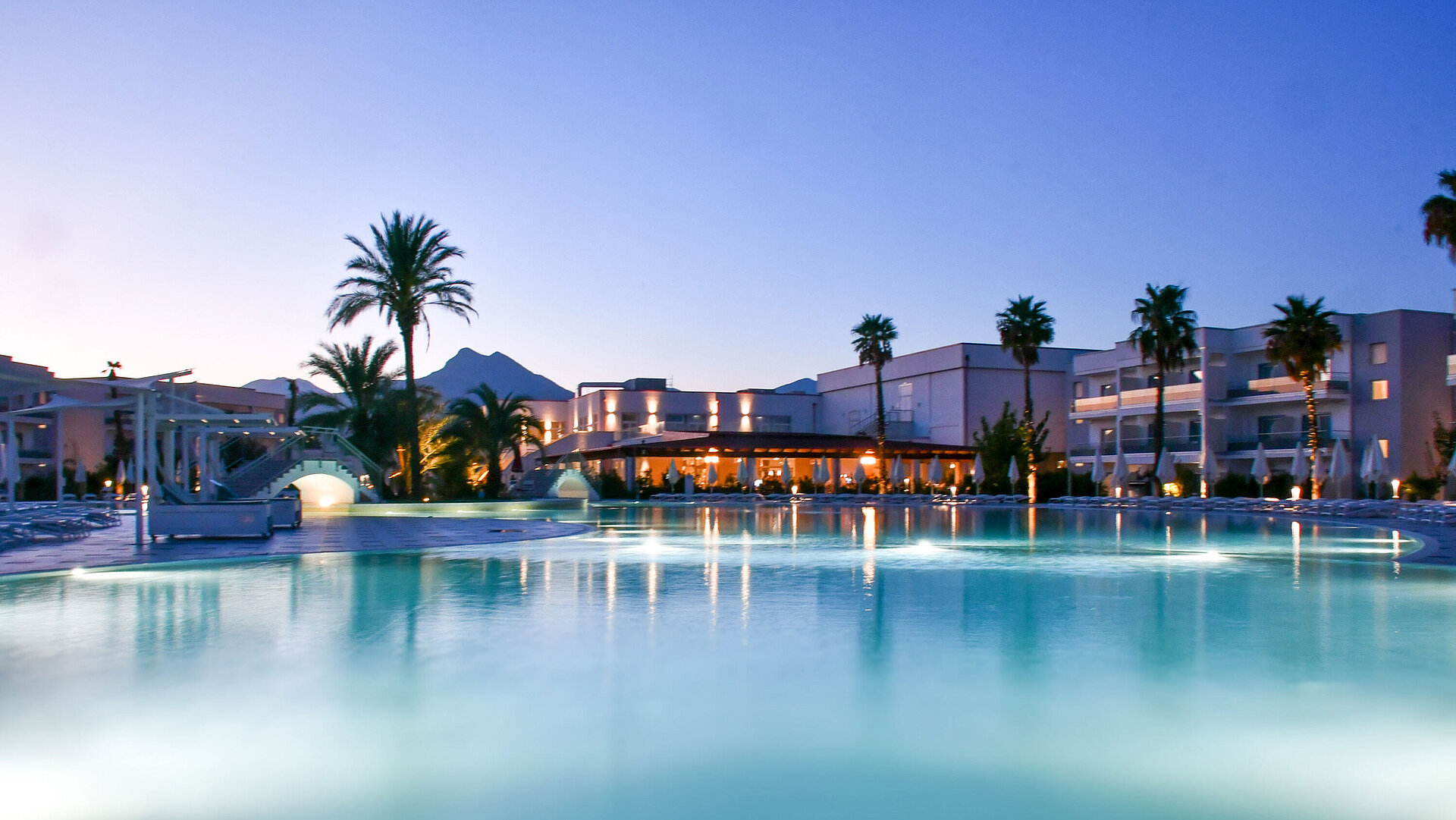 Poolbeleuchtung am Abend im Maritim Resort Calabria mit Palmen und Gebirgskulisse