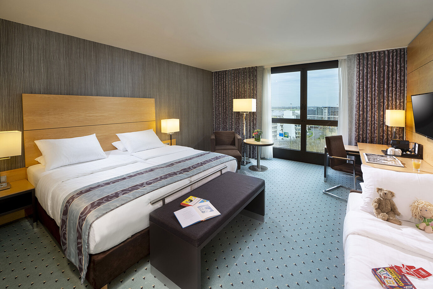 Geräumiges Superior Familienzimmer im Maritim Hotel Düsseldorf mit großem Bett, Zusatzbett und Blick auf die Stadt.