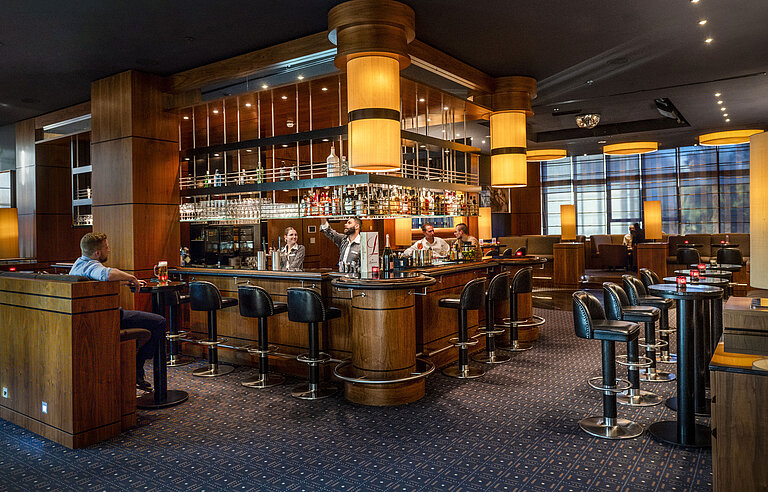 Stilvolle Hotelbar im Maritim Hotel Düsseldorf mit moderner Einrichtung, gemütlicher Atmosphäre und Gästen an der Bar.