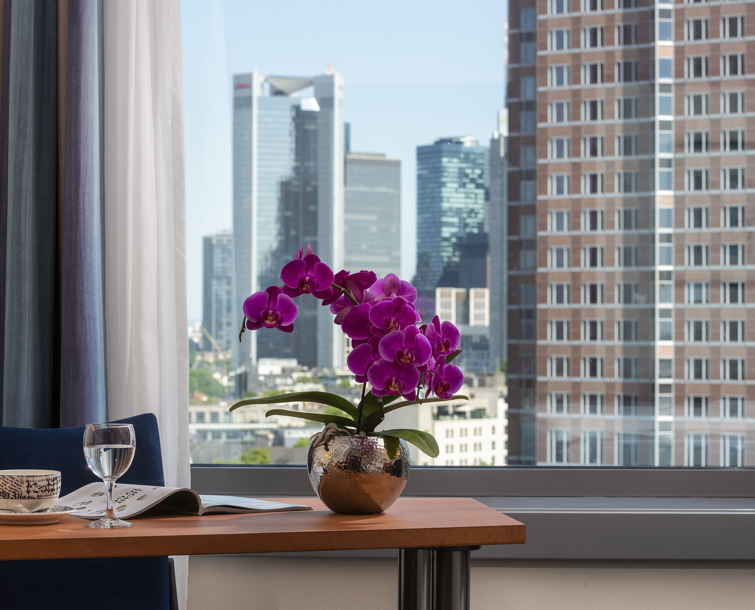 Superior Skyline Zimmer Ausblick aus dem Zimmer im Maritim Hotel Frankfurt mit Skyline-Panorama, Schreibtisch und eleganter Orchidee.