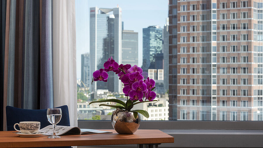 Ausblick aus dem Zimmer im Maritim Hotel Frankfurt mit Skyline-Panorama, Schreibtisch und eleganter Orchidee.