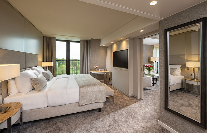 Elegantes Schlafzimmer mit großem Bett,stilvollem Interieur und bodentiefen Fenstern mit Ausblick im Maritim Hotel Ingolstadt