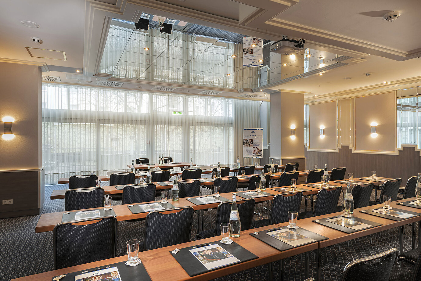 Tagungsraum mit Fensterfront, Tischen und Wasserflaschen im Maritim Hotel München