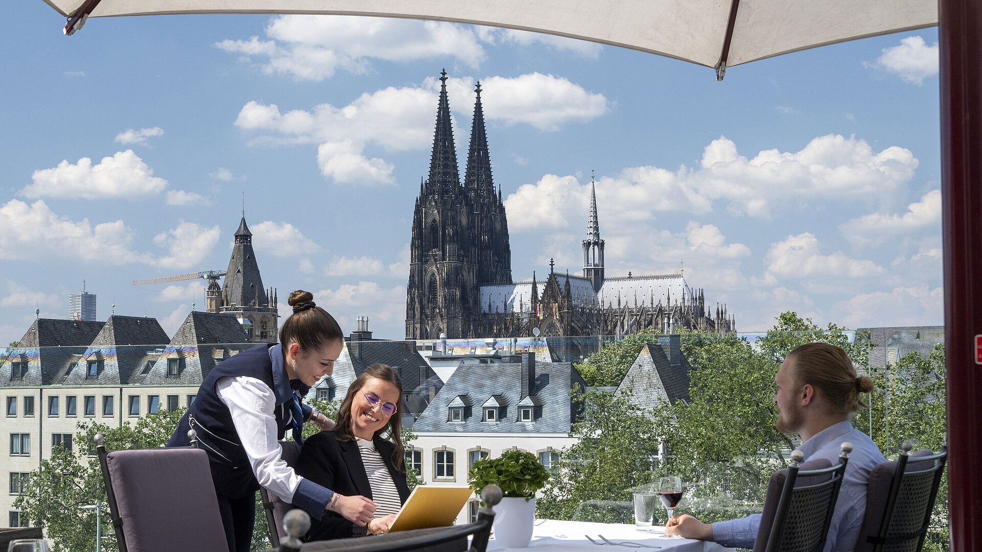 Gäste genießen den Service auf der Dachterrasse des Maritim Hotels Köln mit Blick auf den Kölner Dom und die Altstadt.