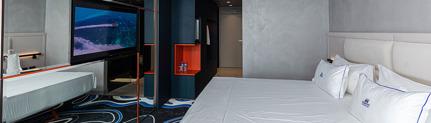Geräumiges Zimmer im Maritim Resort Marina Bay mit großem Spiegel, TV und Doppelbett