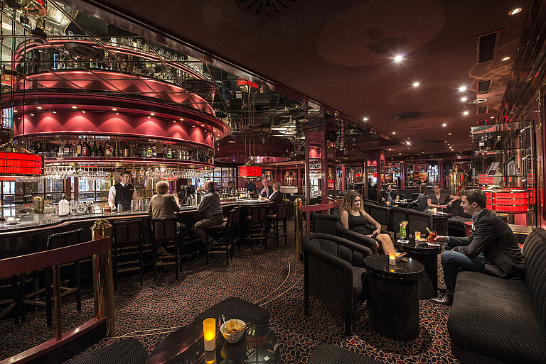 Gäste genießen Drinks in der atmosphärisch beleuchteten roten Hotelbar im Maritim Hotel Stuttgart