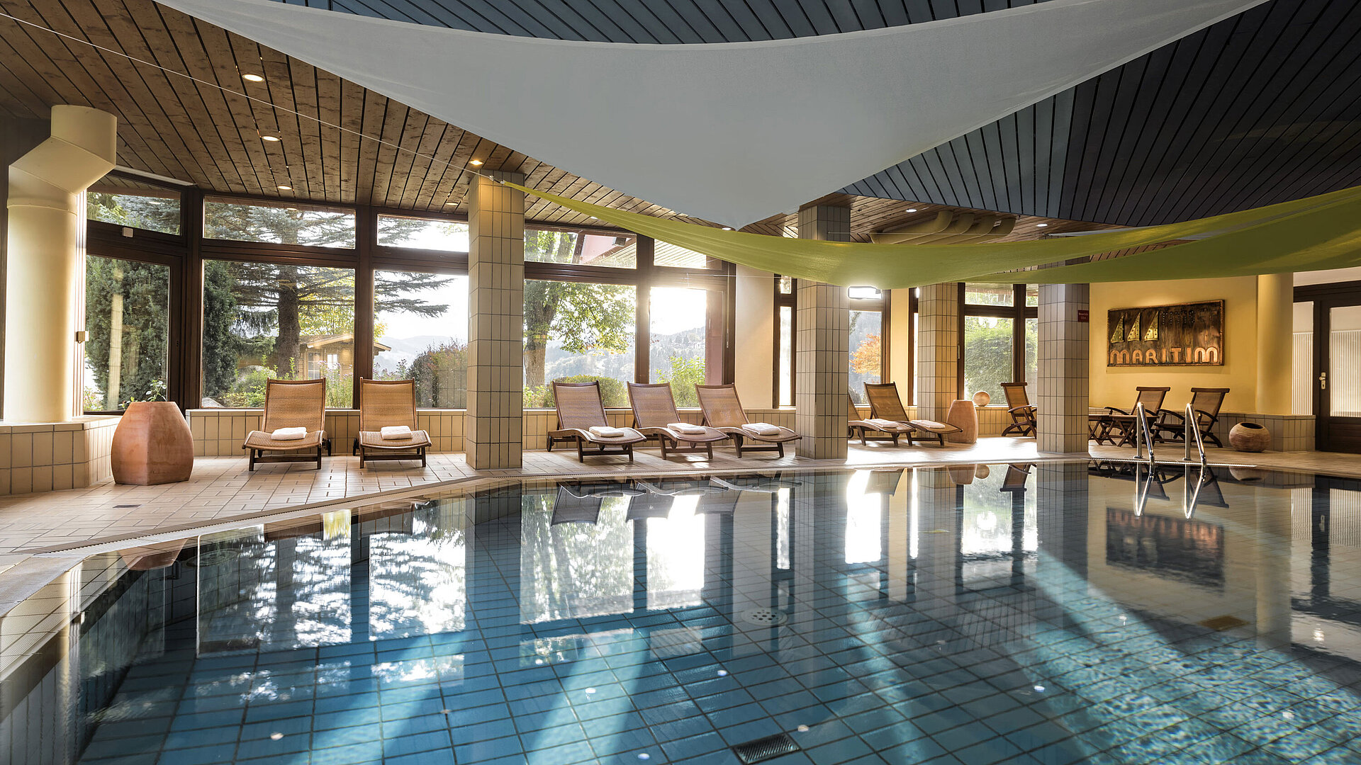 Schwimmbad Heller Innenpool mit Liegestühlen und Gartenblick im Maritim Hotel Titisee
