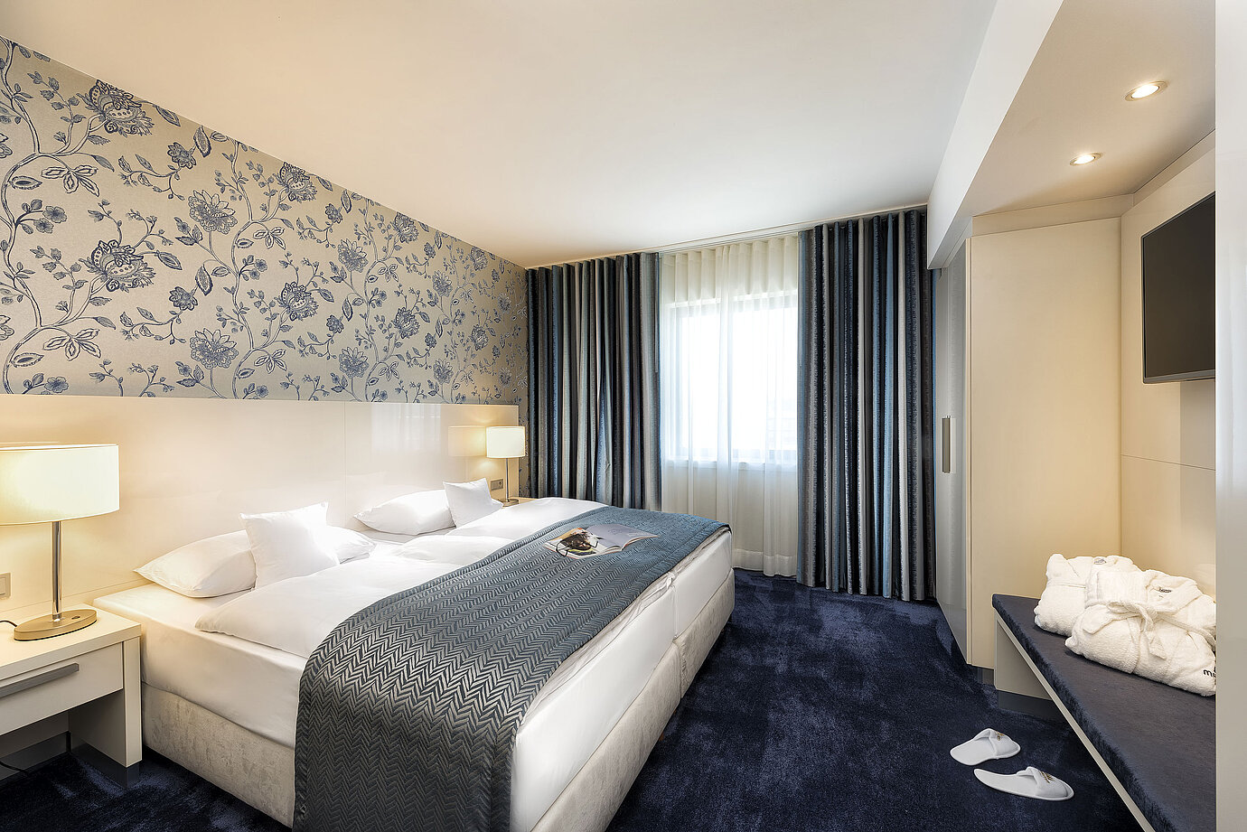 Elegante Suite im Maritim Hotel Bonn mit einem großen Bett, blauer Bettdecke und stilvollem Dekor.