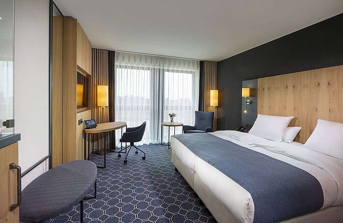 Geräumiges Doppelzimmer im Maritim Hotel Ingolstadt mit Schreibtisch, Sitzbereich und Balkon.