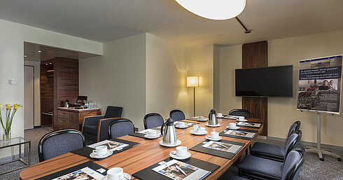 Konferenzraum mit Holztisch, Stühlen und Präsentationstechnik im Maritim Hotel München
