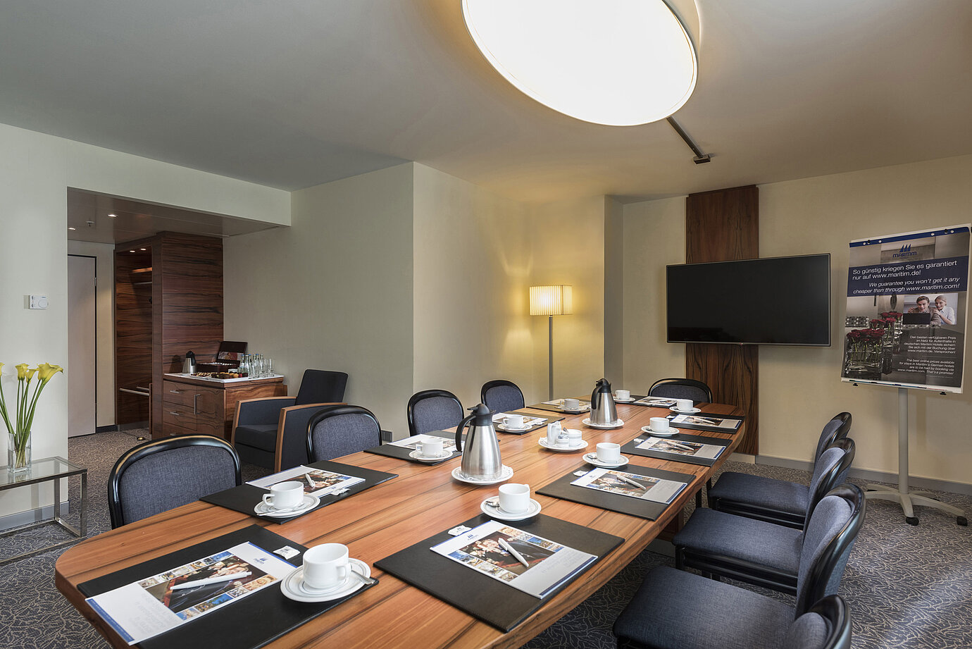 Konferenzraum mit Holztisch, Stühlen und Präsentationstechnik im Maritim Hotel München