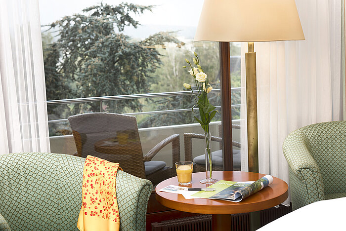 Gemütliche Sitzecke im Maritim Hotel Bad Salzuflen mit Blick auf den Balkon und grüne Umgebung