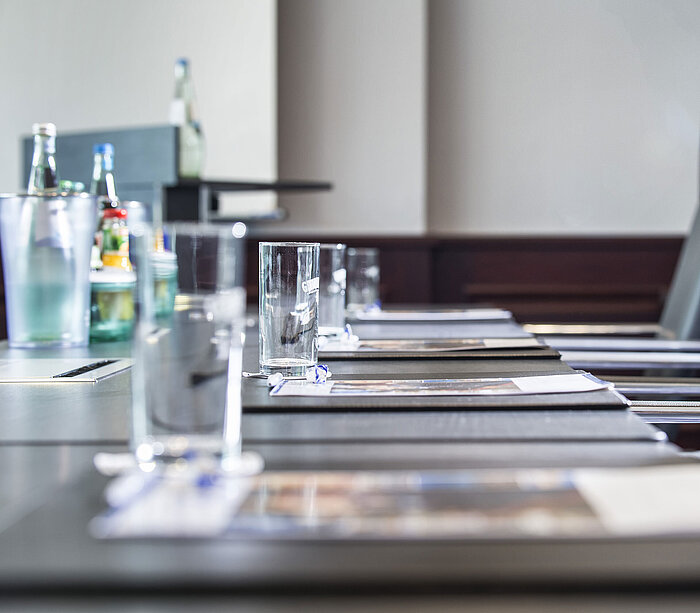 Nahaufnahme eines stilvoll gedeckten Konferenztischs mit Gläsern und Schreibunterlagen im Maritim Hotel Hannover.