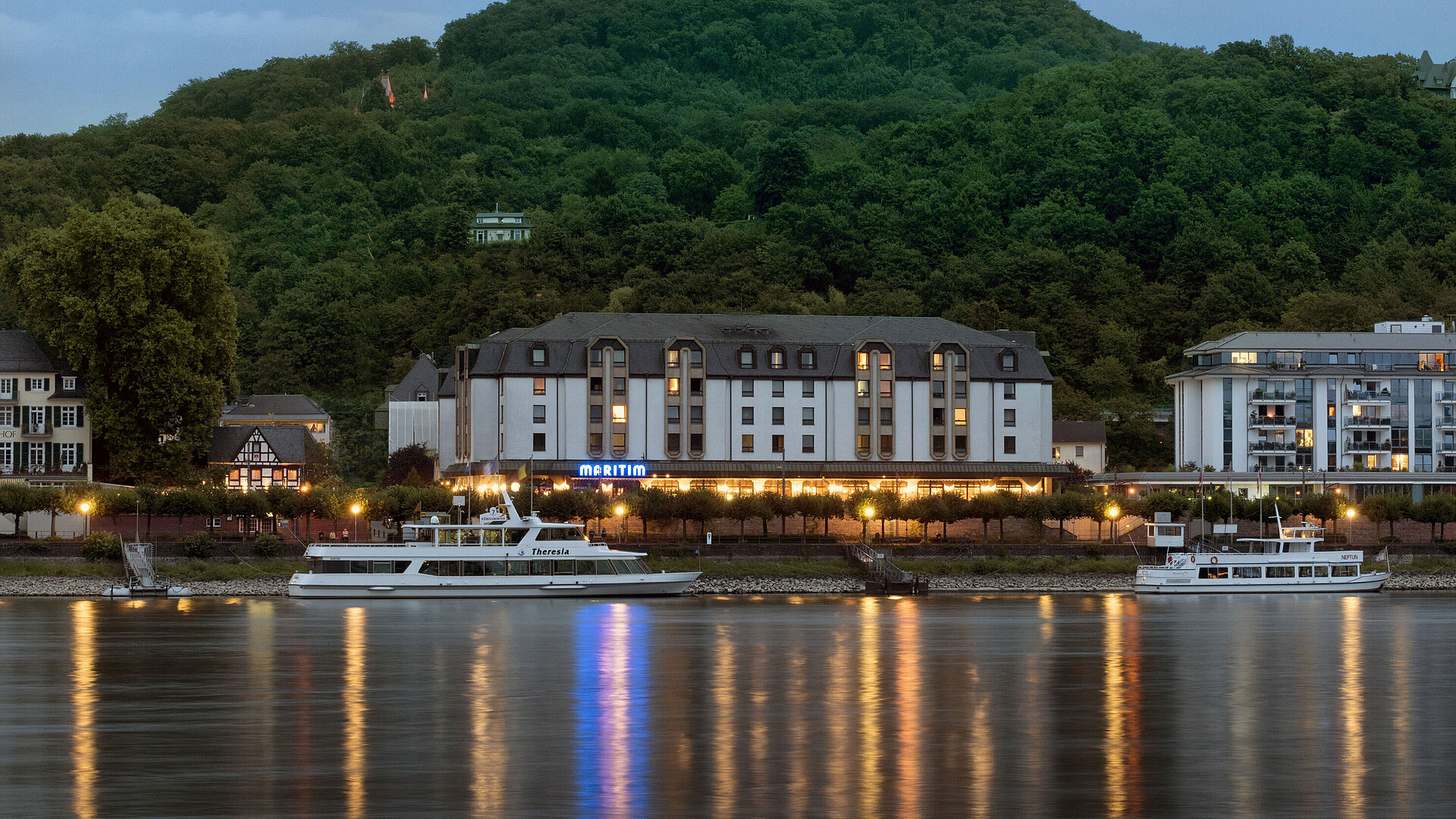 Das Maritim Hotel Königswinter bei Nacht mit stimmungsvoller Beleuchtung und Blick auf den Rhein.
