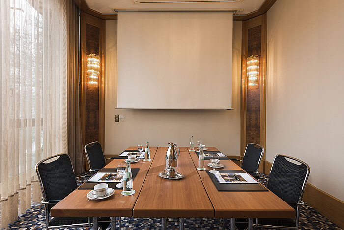 Kompakter Besprechungsraum mit Leinwand, Tageslicht und Konferenztisch im Maritim Hotel Ulm.