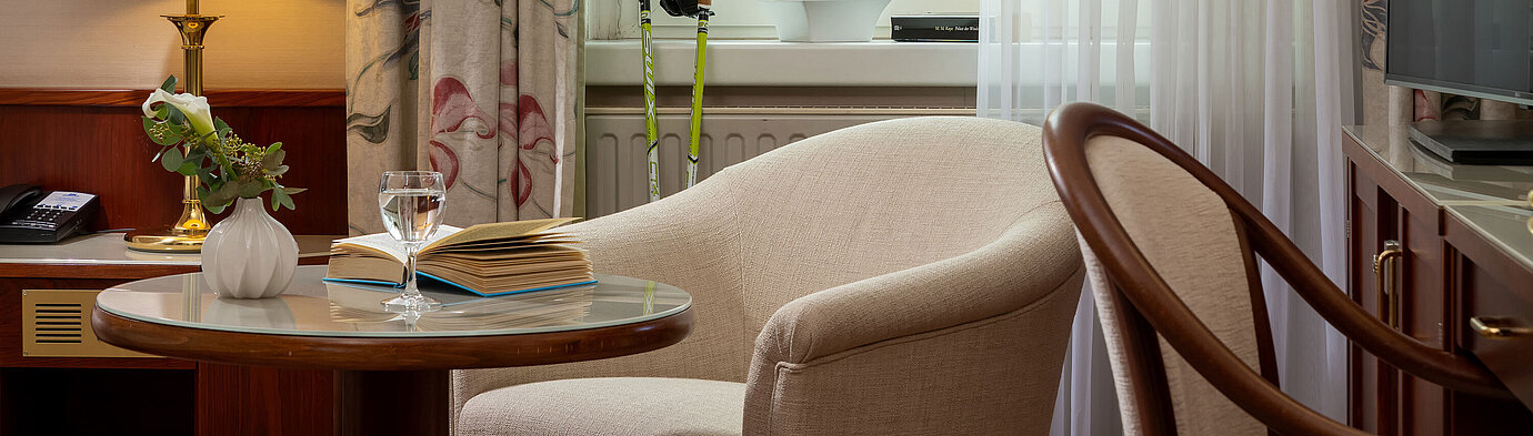 Sitzecke im Classic Einzelzimmer mit Sessel, Tisch, Lampe und Blick durchs Fenster im Maritim Hotel Bad Wildungen.