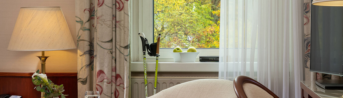 Classic Einzelzimmer Sitzecke im Classic Einzelzimmer mit Sessel, Tisch, Lampe und Blick durchs Fenster im Maritim Hotel Bad Wildungen.