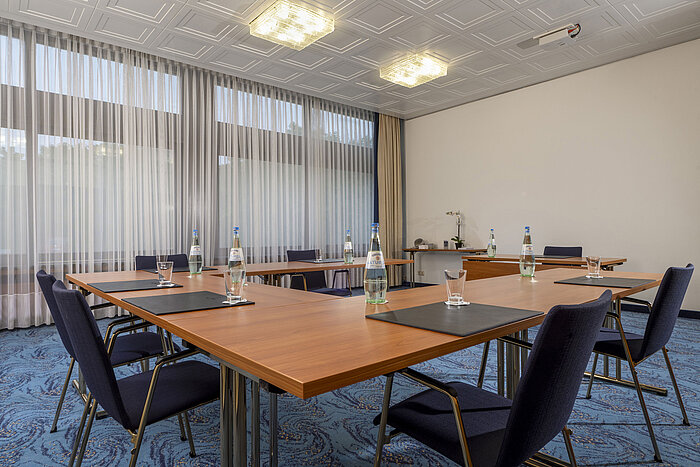 Tagungsraum mit U-Form, Tageslicht, blauen Stühlen und hellem Vorhang im Maritim Hotel Travemünde