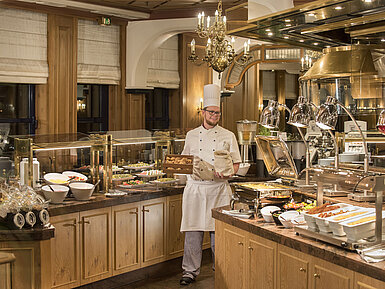 Frühstücksbuffet im Restaurant "Rôtisserie" im Maritim Hotel Bonn mit einer Auswahl an Speisen und einem freundlichen Koch.