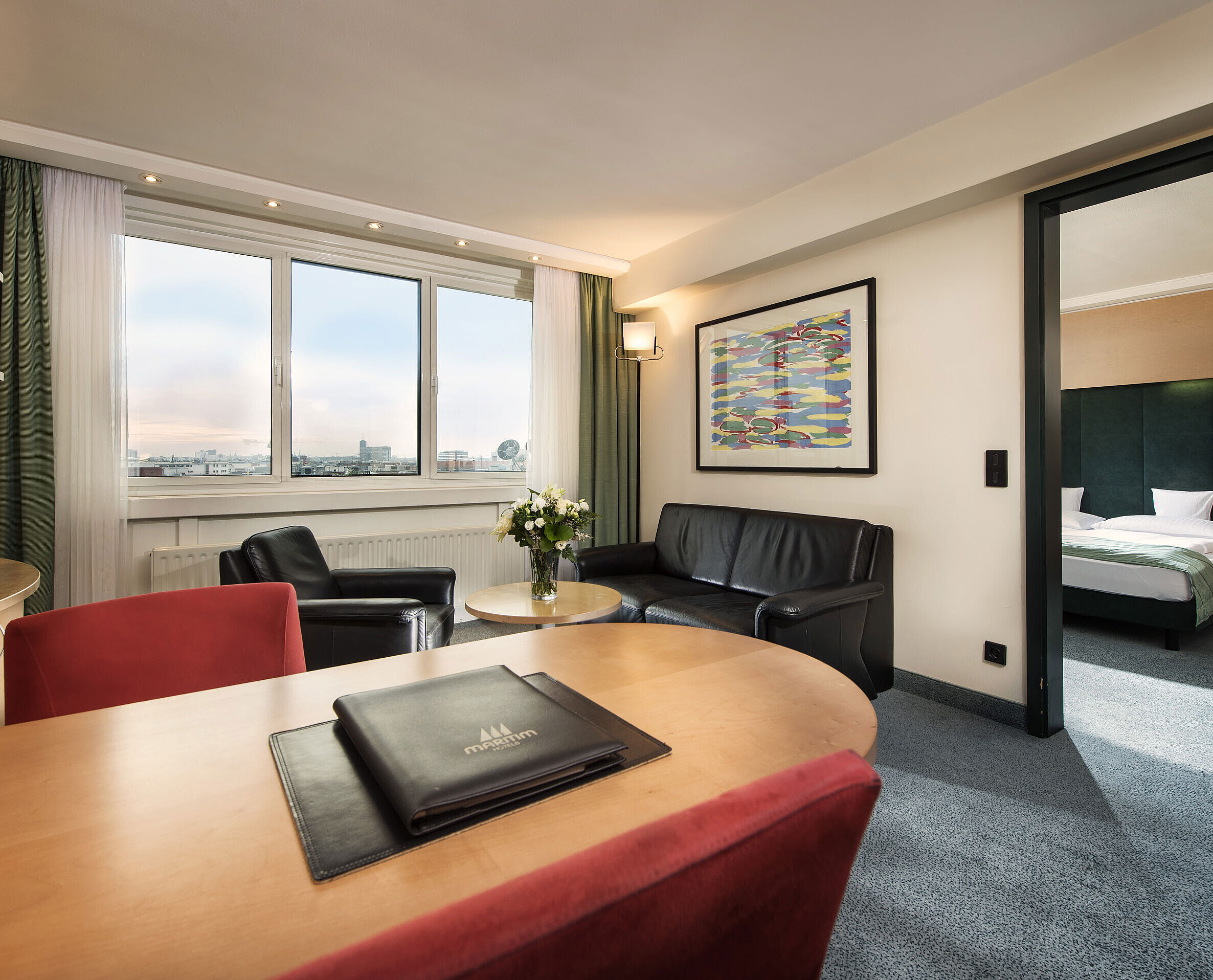 Familiensuite Junior-Suite im Maritim proArte Hotel Berlin mit Wohnbereich, Schreibtisch, Sofa und separatem Schlafzimmer mit Kingsize-Bett.