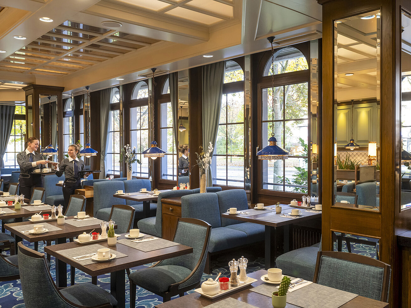 Elegantes Restaurant im Maritim Hotel Darmstadt mit gedeckten Tischen, großen Fenstern und Servicemitarbeitern im Gespräch.