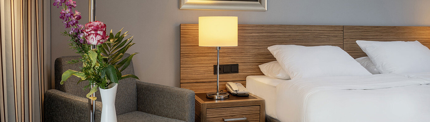 Gemütliche Sitzecke mit Blumenvase neben dem komfortablen Bett im Superior Zimmer des Maritim Hotel Darmstadt