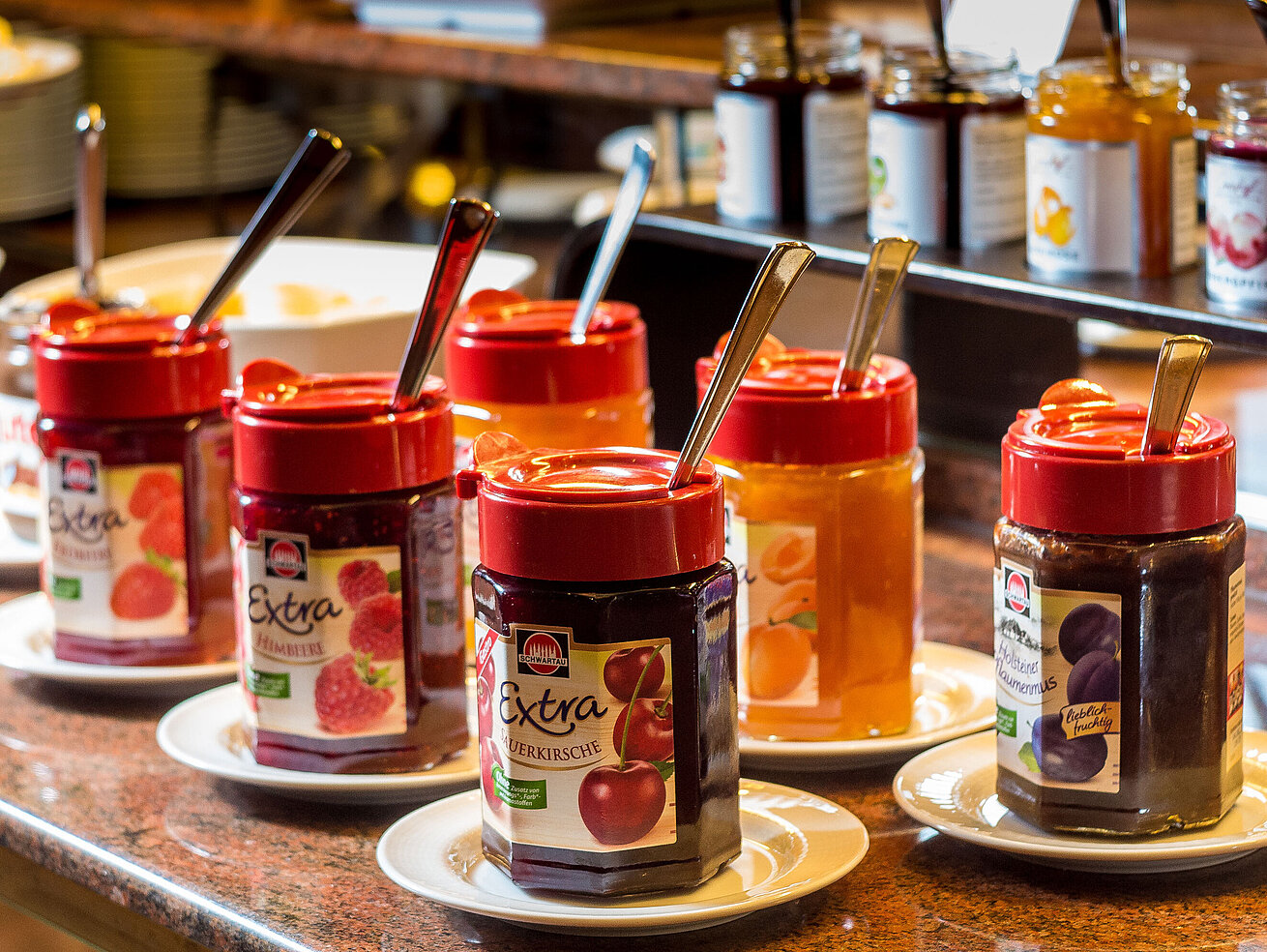 Verschiedene Marmeladen in Gläsern zur Auswahl am Frühstücksbuffet.